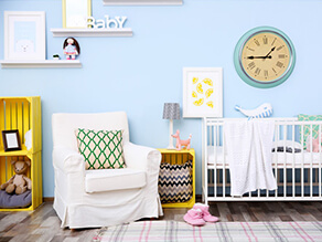 Pale_Blue_Nursery_Painted_Yellow_crates_white_covered_seat_green_pattern_pillow_slippers_rug